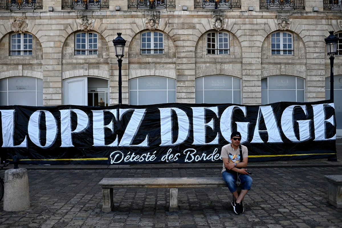 Чоловік сидить на тлі банера Лопес, пішов геть у Бордо, Getty Images